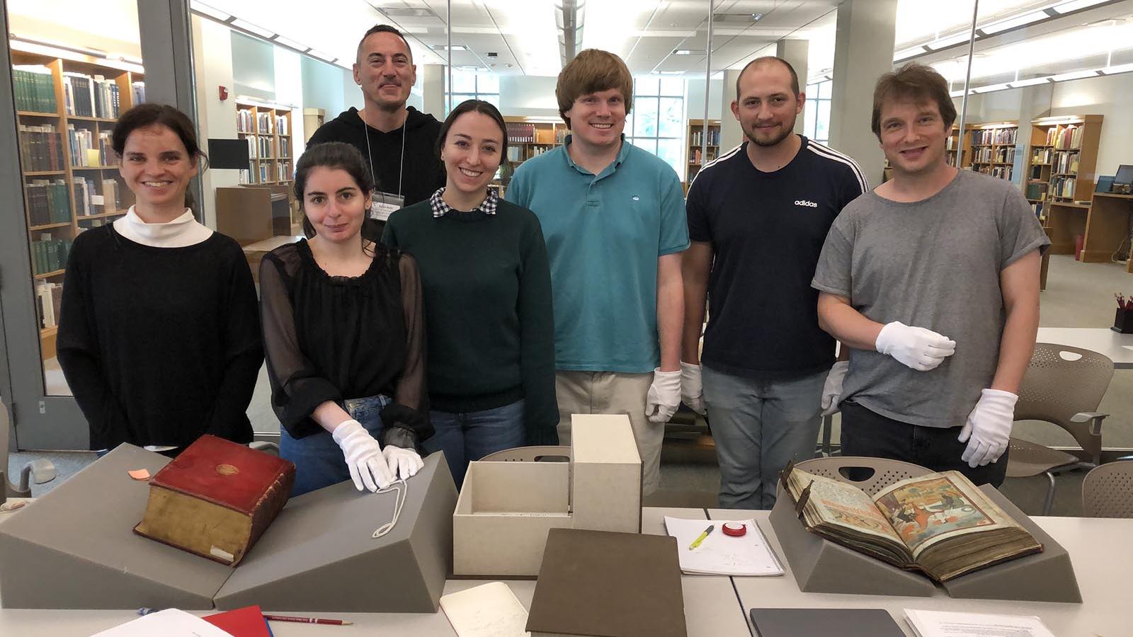Six students and instructor standing behind table of medieval Slavic manuscripts